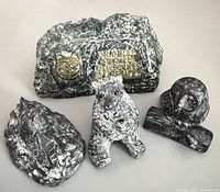 Group shot of four soapstone pieces: plaque, bear, owl, canoe scene