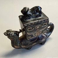 Front angled view showing beast form, lidded vessel, finial