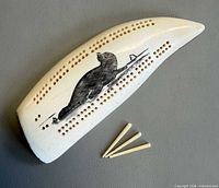 top view showing scrimshaw seal design, cribbage holes, three pegs