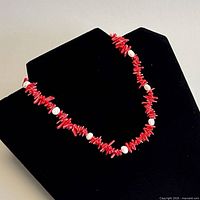 Full view of coral and pearl choker on display stand