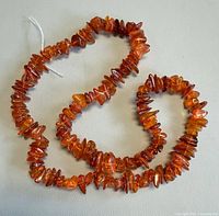 Full length view of amber chip necklace on light surface