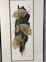 Close view of artwork showing three paper fans, layered black paper, gold threads