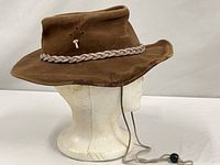 Side view of brown suede bush hat on mannequin head showing brim, hatband and chin strap