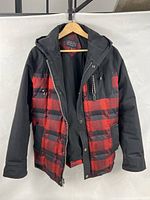 Front view of jacket hanging, showing plaid body and black sleeves
