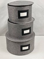 Three grey round fabric storage boxes stacked