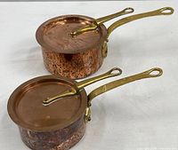 Two copper saucepans with lids and brass handles