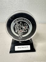 Front view of autographed puck inside case on stand