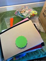 Stack of foam and felt sheets with bag of mixed craft pieces