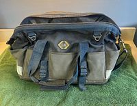 Front view of CK canvas tool bag showing logo, handles, pockets, shoulder strap