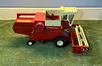 Right front view of red International Harvester metal toy combine showing header and cab