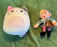Front view of Squishmallows cat plush and Hermey elf plush