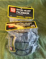 Front view of three sealed Wilson batting helmet facemasks