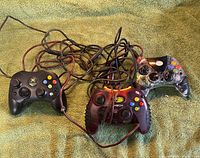 Front view of three wired Xbox controllers showing layouts and colors