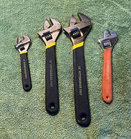 Four adjustable wrenches laid out showing full view and handles