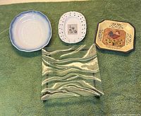 Front view of four assorted decorative plates on green background