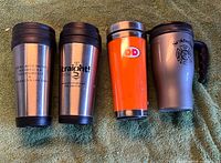 Front view of four insulated travel mugs showing logos and colors