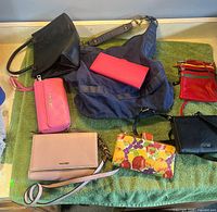 Eight purses and wallets on green towel