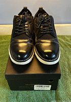 Front view of pair of Meijiana black shoes on original box