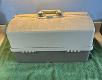 Front view of closed two-tone grey tackle box on green towel
