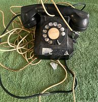Entire phone with handset and tangled cords on green background