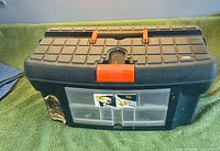 Front view of black plastic toolbox with red latch and clear organizer drawers