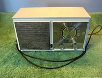 Front view showing speaker grille, dial, controls, and branding