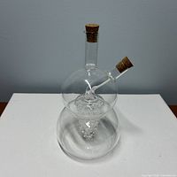 Full view of clear glass 2-chamber cruet with corks