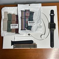 Full lot view: watch, charger, packaged and loose bands, screen protector