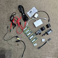 All items laid out on carpet including RAM sticks, cables, adapters, battery, plastic parts