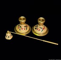 Pair of brass candlesticks and matching snuffer on black background