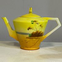 Full view of yellow porcelain teapot with angular handle and spout