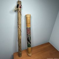 Both rainsticks standing upright against wall