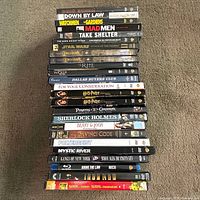 Full stack of 25 DVD and Blu-ray cases laid flat, spines readable