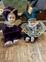 Both jester dolls side by side on wood surface