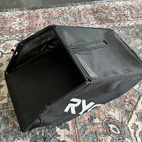 Side view of Ryobi grass catcher showing fabric body, frame, logo