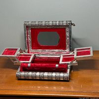 Jewelry box open showing mirror, folding trays, red velvet lining
