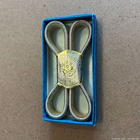 Fastener clip in box, top view showing St. George logo plate and looped springs
