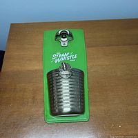 Front view showing green backplate, metal opener, cap catcher, Steam Whistle logo