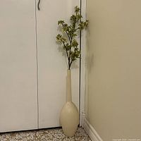 Full view of tall ivory Umbra vase with faux stems for scale