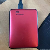 Front view showing red casing, WD logo, My Passport text, USB cable attached