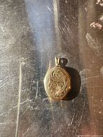 Front view of engraved oval gold locket pendant