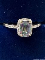 Front view of ring showing mystic topaz, diamond halo and partial diamond shoulders
