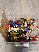 Plastic bin on scale showing 4175 g of assorted LEGO pieces and baseplate