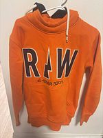Front view showing RAW logo, color, pocket, drawstring