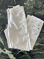 Front view of folded white jeans showing lace cut-out detail