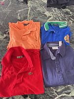 Four folded polo shirts: orange, blue, red, navy