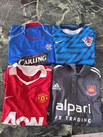 Four folded soccer jerseys displayed on surface