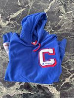 Folded blue Champion hoodie with C patch visible