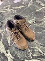 Top view of the pair of olive green Puma boots on surface