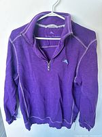 Front view of purple Tommy Bahama quarter-zip sweater showing collar, zipper, logo, contrast stitching